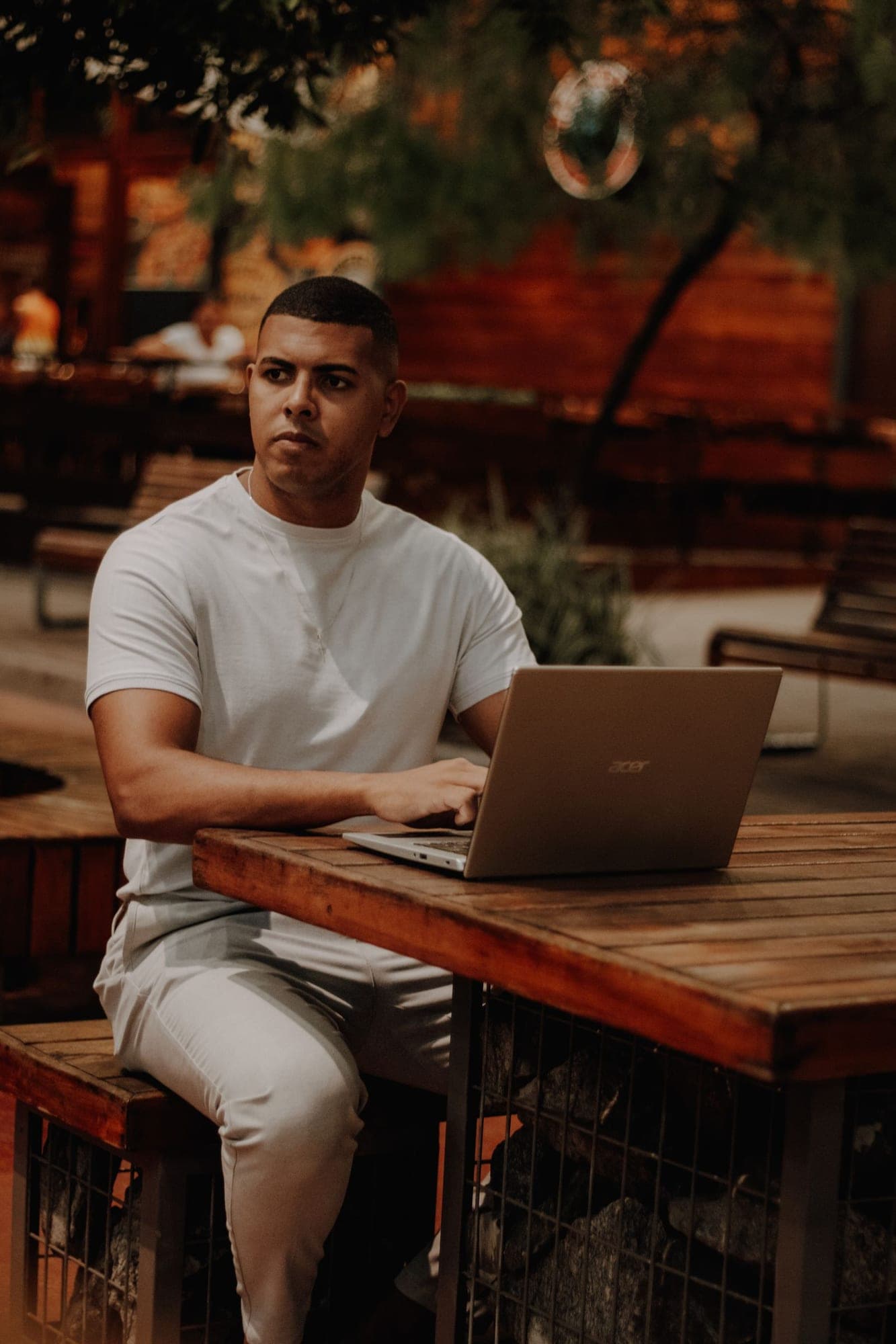 Emprendedor joven trabaja en su portátil en la mesa de madera de un café al aire libre
