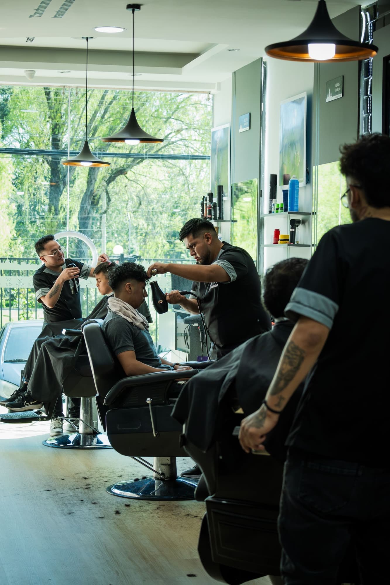 Peluqueros atienden a sus clientes en las sillas de una peluquería con luz natural